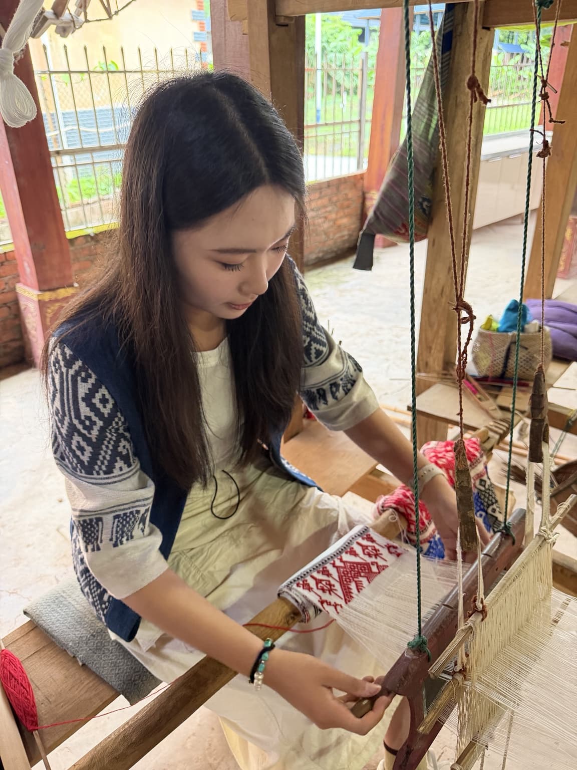 ZEWU founder working at a traditional loom in a contemporary craft studio.